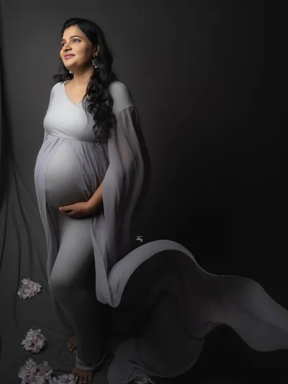 A full-length view of this gorgeous grey gown, with its long train spread out. The soft floral details on the floor add a touch of delicate contrast.