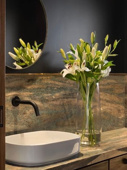 In this powder room for the West Coast Residence, we paired a richly-grained stone countertop with a dark, textured wall. The simple vessel sink and minimalist black tap keep the focus on the beautiful materials.