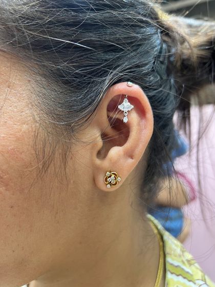 A delicate gold and silver combination, with a small hanging in the helix and a floral lobe stud.