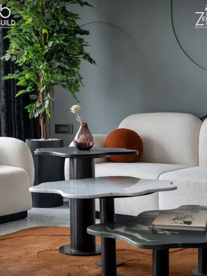 The living area in 'The House of Arcs' features unique, petal-shaped nesting coffee tables in different marbles. These custom pieces add an organic and artistic touch to the room.