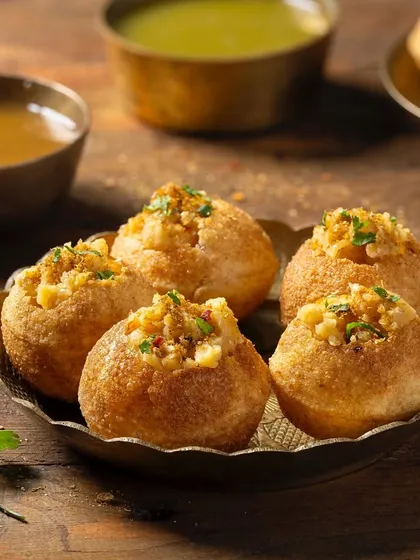 Golgappe (Pani Puri) served in a brass bowl for Chhappan Bhog. The styling focuses on the classic street food experience, complete with spicy and sweet water.