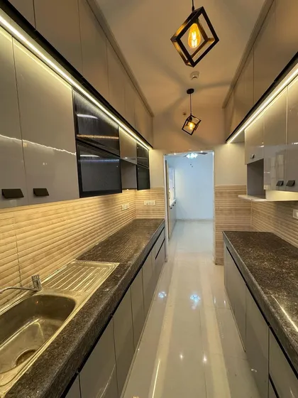 We designed this sleek parallel kitchen to be both beautiful and functional. It features high-gloss grey laminate cabinets, a durable granite countertop, and integrated under-cabinet LED lighting that makes the workspace bright and inviting.