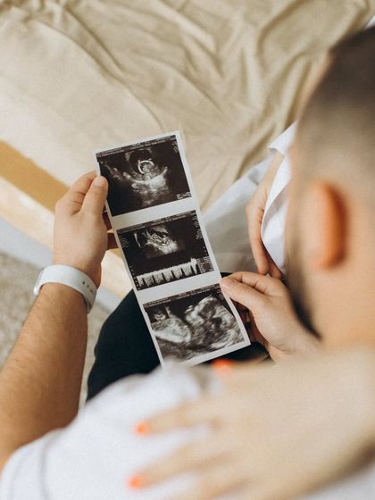 A close-up, intimate shot of a couple looking at their ultrasound photos together. This captures the private, exciting moments of anticipation before the baby arrives.