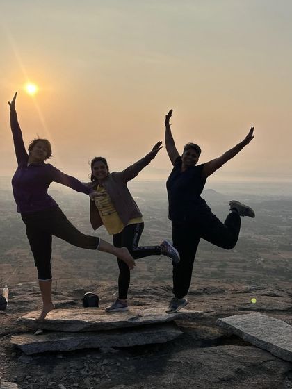 Having some fun at the summit. Three trekkers strike a pose against the beautiful morning sky.