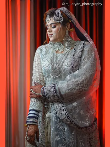 A graceful portrait with a red background. The bride looks down, creating a serene and contemplative mood that highlights the elegance of her attire and posture.