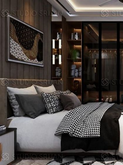 A bedroom with a dark, moody aesthetic, featuring a floor-to-ceiling upholstered headboard and a glass-fronted wardrobe with internal lighting.