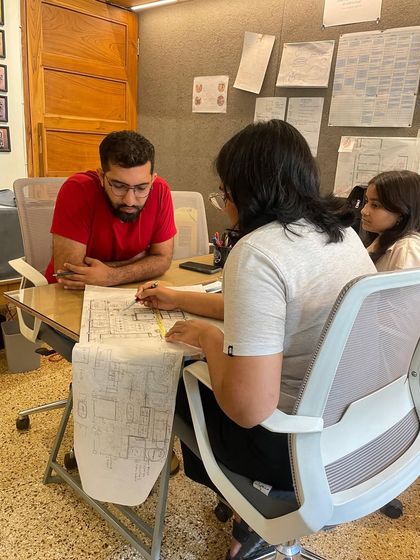 A candid shot of our team collaborating around a desk, reviewing architectural plans. This captures the focused, hands-on energy of our studio.