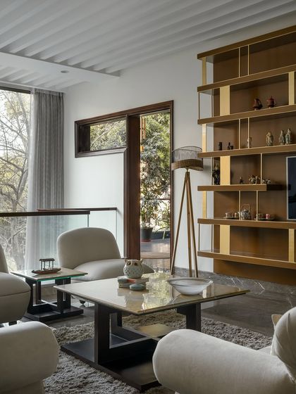 The living room at Twin Villa opens up to views of the garden. The interior design is kept clean and modern, with a neutral palette and high-quality materials that complement the architectural focus on light and nature.