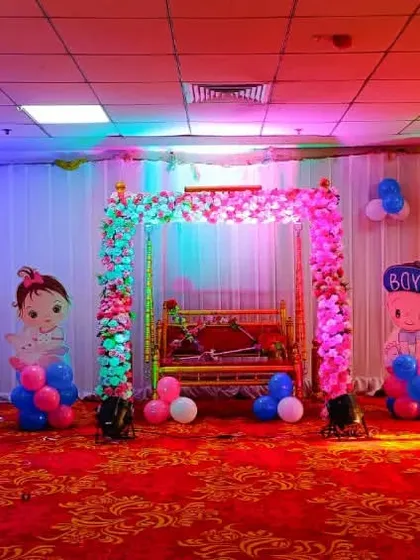 For this large-scale naming ceremony in a hall, we designed a complete stage with multiple elements. The decor includes a traditional baby cradle (palna), a large crescent moon arch made of flowers, and cute baby character cutouts, all brought to life with colorful lighting.