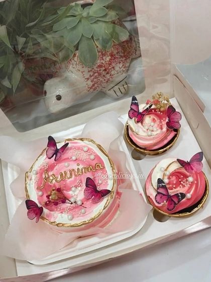 A close-up of the personalized butterfly-themed bento box. The combination of a mini cake and cupcakes makes for a wonderful and complete gift.