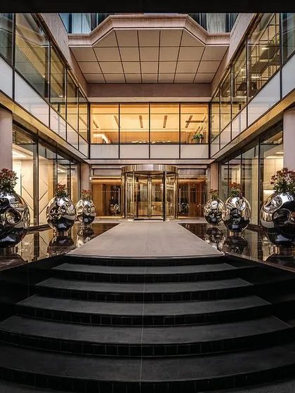 A symmetrical view of the entrance steps and open-air courtyard, flanked by large, polished steel planters that add a modern touch to the classic architecture.