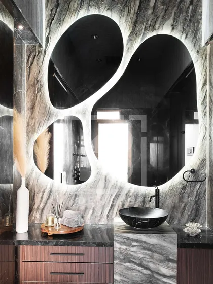 Another example of a statement mirror. The organic, free-form shape with backlighting creates a dramatic and artistic focal point in this modern bathroom.