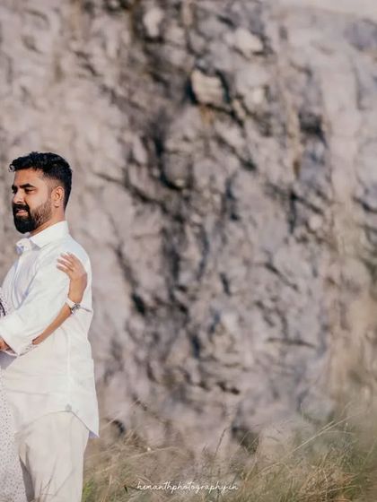 A beautiful portrait of the expecting couple, showcasing their coordinated white outfits against the rustic, natural landscape.