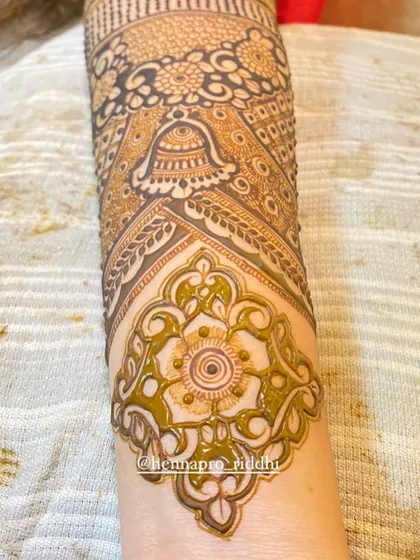 A close-up look at the fine details and finishing touches. This section of an arm design shows a delicate floral motif and a traditional bell, highlighting the clean lines and shading.