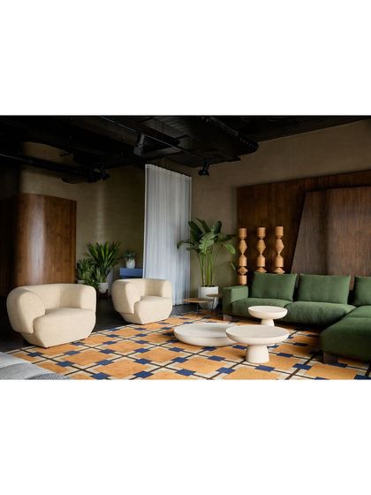 A wide view of a living area setup, showing how different furniture groupings can create a cohesive and inviting environment. The neutral walls and dark floor act as a canvas for the furniture.