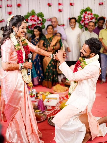 A beautiful proposal moment during the engagement ceremony. The bride's elegant South Indian look, complete with a pink silk saree and half-up hairstyle, is on full display.