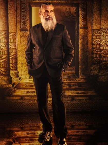 A dramatic, ancient temple entrance with flaming torches, created with projection. The setting provides a powerful, almost mythical backdrop for this sharp, modern suit.