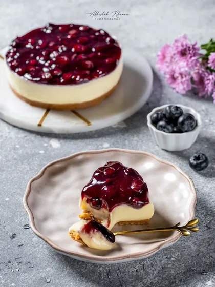 A slice of decadent blueberry cheesecake, captured for Ferns N Petals Luxe. This dessert photography focuses on the creamy texture and the glistening fruit topping, creating a premium and indulgent visual for their bakery catalog.