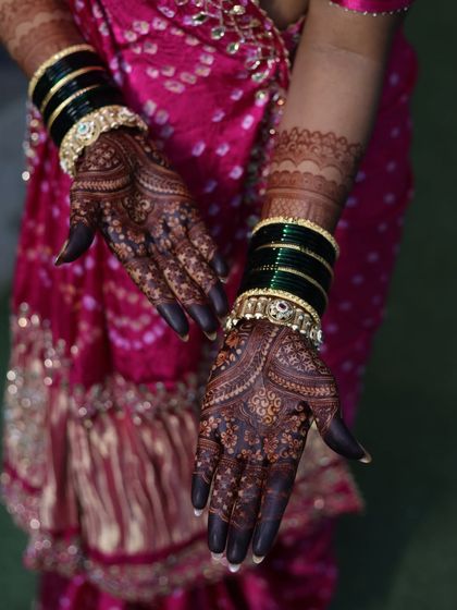 A gorgeous shot of a bride's hands after the henna stain has developed, adorned with traditional green bangles.