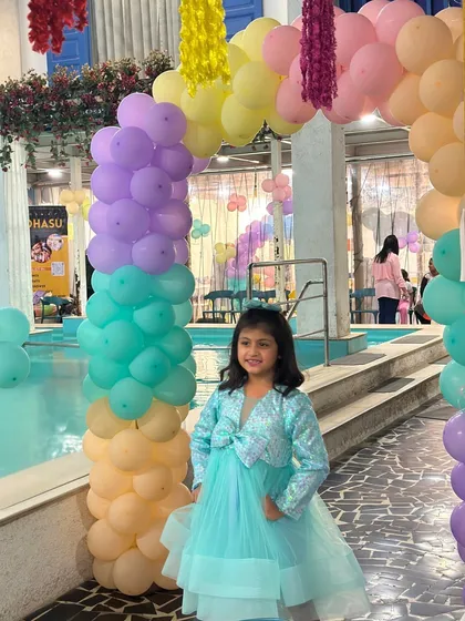 The birthday girl standing in front of a beautiful pastel rainbow balloon arch. Our in-house decor service can match any color scheme you have in mind.