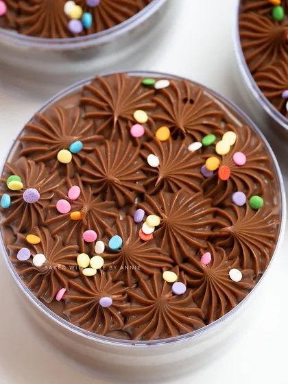 A close-up of my Belgian Milk Chocolate Cake Tub. Topped with piped ganache and colorful confetti, this nostalgic and delicious treat is perfect for the festive season and easy to serve.
