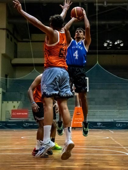 An All-Star player goes for a layup against a strong defense during a charity basketball match. This action shot captures the competitive spirit of the games hosted at our facility.