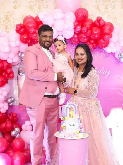 Family celebrations call for coordinated style. This family looks picture-perfect in matching shades of pink for a first birthday party, with a smart suit for him and an elegant gown for her.