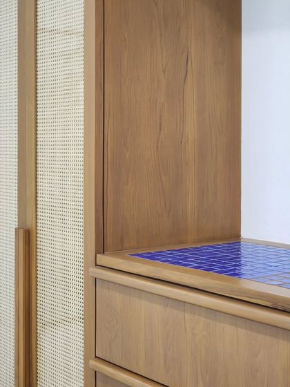 A close-up of a storage unit featuring a vibrant blue tile countertop next to natural wood and cane. I enjoy introducing unexpected pops of color and texture to create focal points and add character to my furniture designs.