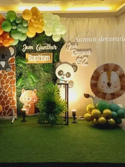 A cute woodland and jungle animal theme for a baptism and second birthday. This setup uses an artificial grass wall, animal cutouts like a lion, panda, and deer, and a balloon garland in earthy tones.