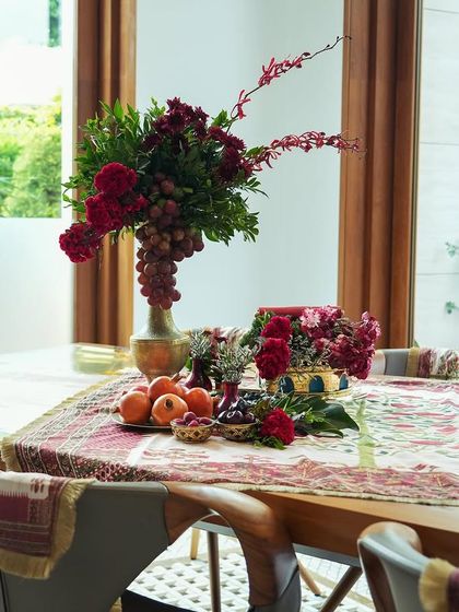 A long view of the dining table from 'दाड़म ka Bageecha', showing the beautiful runner, floral arrangements, and the warm, inviting atmosphere.