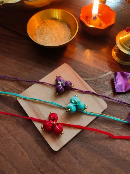 These beautiful floral rakhis are made from fabric beads and come in purple, teal, and red. Each one is carefully crafted by hand.