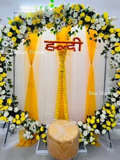 A bright and sunny Haldi decoration with a circular frame covered in yellow and white flowers.
