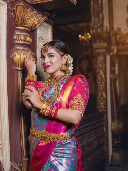 A close-up portrait against an ornate backdrop. The makeup is flawless and camera-ready.