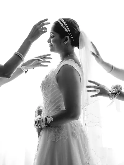A candid black and white moment of the bride getting ready, with hands adjusting her veil. This shot tells a story of support and anticipation.