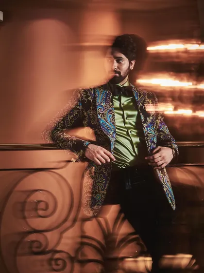 A motion shot of Ankush Bahuguna in the printed jacket, capturing the dynamic energy of the ensemble. The play of light and shadow highlights the texture and colors of the fabric.