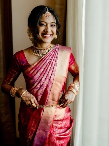 That radiant bridal smile says it all! For this lovely South Indian bride, we created a fresh, dewy makeup look that photographed beautifully and paired it with a traditional yet soft bridal updo.