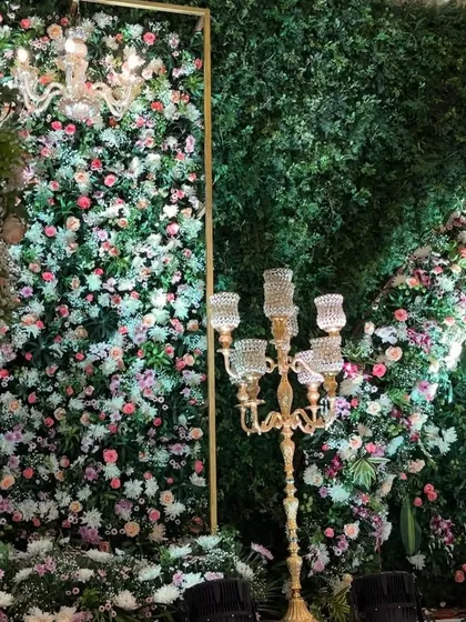 A close-up of a lavish floral wall, densely packed with pink, white, and peach roses, accented by a crystal chandelier. This opulent design is perfect for creating a glamorous and romantic photo backdrop.