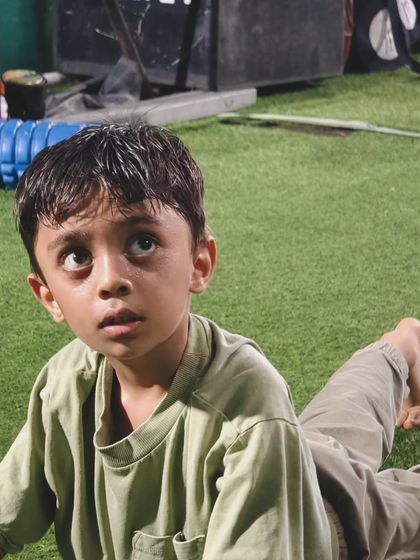 The look of pure focus. This young athlete is fully engaged while holding a stretch, learning discipline and body control.