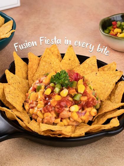 Our unique Nachos Chaat is a fun fusion dish. Crispy tortilla chips are topped with a fresh salsa of corn, onions, and tomatoes, creating a fiesta in every bite.