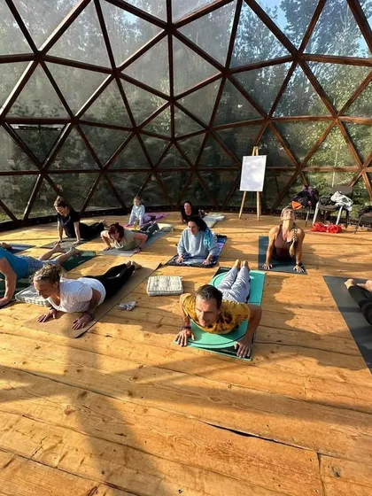 Students are seen here practicing Bhujangasana (Cobra Pose) in unison. This back-bending asana is excellent for strengthening the spine and opening the heart, a common pose in our Hatha yoga classes.