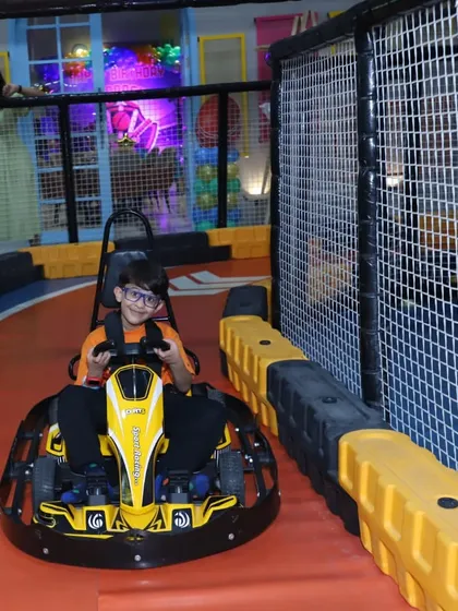 A view from the driver's seat! A child enjoys the thrill of navigating our winding go-kart track, with safety barriers ensuring a secure ride.