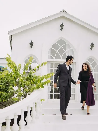 A candid shot of the couple descending a grand white staircase. This feels like a scene from a classic movie, full of elegance and movement.