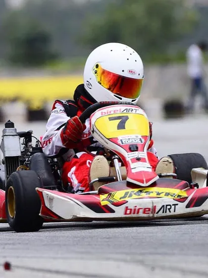 A Birel ART driver in kart number 7, focused on the apex of a corner during a tight race in the Indian Rotax Championship.