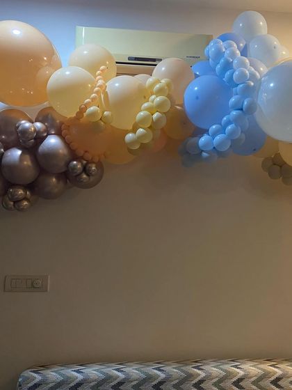 A soft and dreamy balloon garland to decorate the wall for a baby's arrival. The mix of pastel blue, yellow, and metallic balloons creates a gentle and celebratory touch to the room.