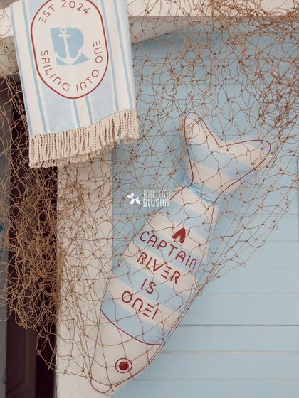 A close-up of the bespoke party details, including a personalized towel and a fish pillow caught in a net.