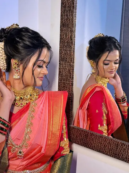 A moment of reflection for the bride. This profile showcases the intricate hair bun, glowing skin, and the beautiful drape of her pink and red `Paithani` saree.