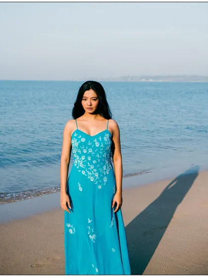 A simple and beautiful full-length portrait against the vastness of the ocean. The composition is clean and focuses on the model.