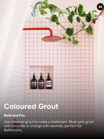 Coloured grout is a fun way to make a statement. Here, blush pink grout paired with simple white tiles and a red shower head creates a bold and playful bathroom design.