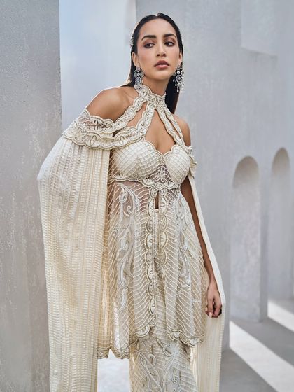 A closer view of the ivory sharara set's embellished top, with cold-shoulder cuts and floor-sweeping sleeves.
