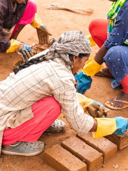 Women learning to make compressed stabilized earth bricks (CSEB) by hand. Our workshops focus on practical, transferable skills that empower women to use local materials for building.